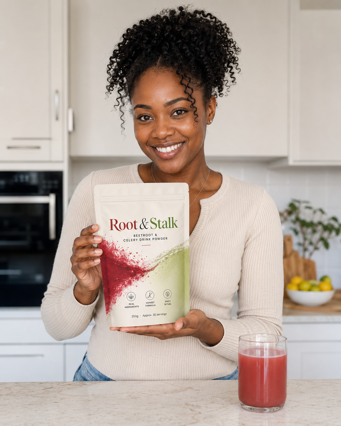 Person holding Root & Stalk pouch in a bright kitchen with a pink drink on the counter